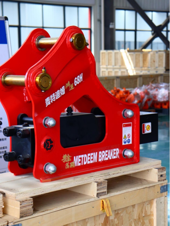 Red METDEEM 68H hydraulic rock breaker on wooden pallet in factory workshop